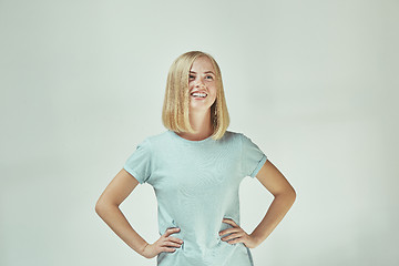 Image showing The happy freckled woman standing and smiling against gray background.