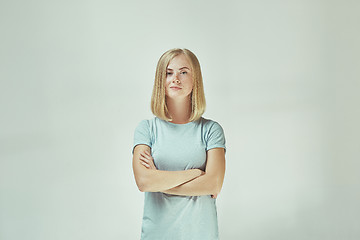 Image showing The happy freckled woman standing and smiling against gray background.