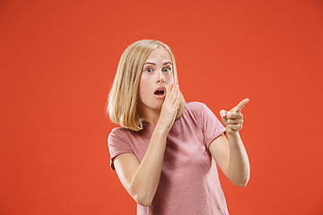 Image showing The young woman whispering a secret behind her hand over red background