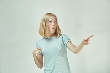 Image showing The young woman whispering a secret behind her hand over gray background