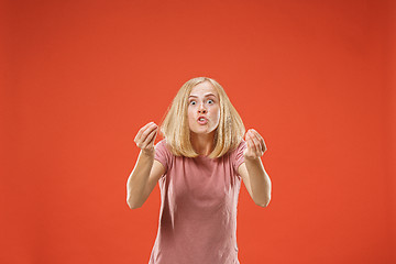 Image showing Beautiful female half-length portrait isolated on red studio backgroud. The young emotional surprised woman