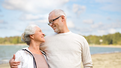 Image showing happy senior couple hugging over beach background