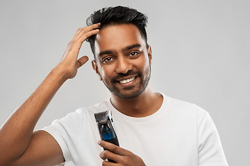 Image showing smiling indian man with trimmer touching his hair