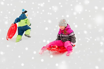 Image showing happy kids sliding on sleds down hill in winter