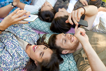 Image showing friends with smartphones chilling at summer park