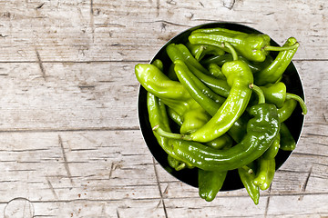 Image showing Fresh green raw peppers in metal bowl on rustic wooden table bac