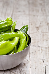 Image showing Fresh green raw peppers in metal bowl on rustic wooden table bac