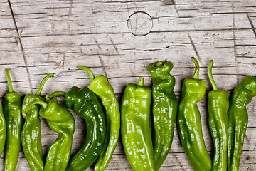 Image showing Fresh green raw peppers on rustic wooden table background. 