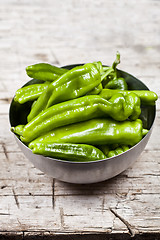 Image showing Fresh green raw peppers in metal bowl on rustic wooden table bac