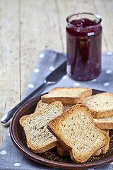 Image showing Toasted cereal bread slices on grey plate and jar with homemade 