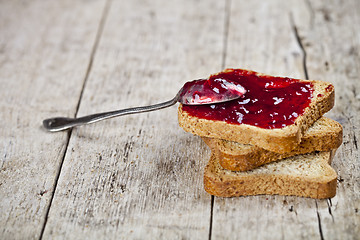 Image showing Toasted cereal bread slices with homemade cherry jam and spoon c