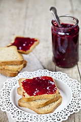 Image showing Toasted cereal bread slices on white plate and jar with homemade