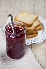 Image showing Jar with homemade cherry jam and fresh toasted cereal bread slic