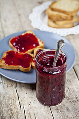 Image showing Homemade cherry jam and fresh toasted cereal bread slices plates