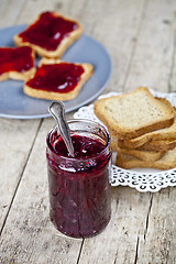 Image showing Homemade cherry jam and fresh toasted cereal bread slices plates