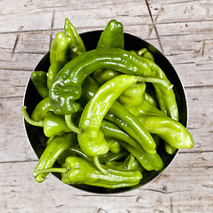 Image showing Fresh green raw peppers in metal bowl on rustic wooden table bac