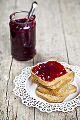 Image showing Toasted cereal bread slices on white plate and jar with homemade