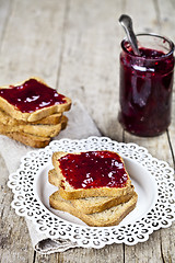 Image showing Toasted cereal bread slices on white plate and jar with homemade