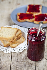 Image showing Homemade cherry jam and fresh toasted cereal bread slices plates