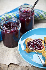 Image showing Fresh cereal bread slices on blue ceramic plate, homemade cherry