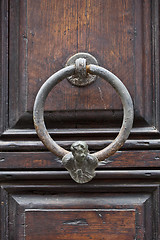 Image showing Ancient italian door knocker on wooden brown door.