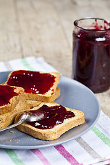 Image showing Fresh toasted cereal bread slices with homemade cherry jam in ja