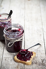 Image showing Fresh cereal bread slices and jars with homemade wild berries  a