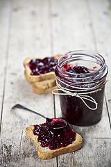 Image showing Toasted cereal bread slices and jar with homemade wild berries j