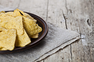 Image showing Mexican nachos chips on brown ceramic plate on linen tablecloth.