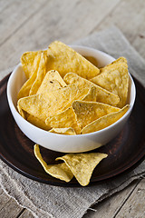 Image showing Mexican nachos chips in white bowl on brown ceramic plate on lin