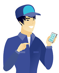 Image showing Young asian mechanic holding a mobile phone.