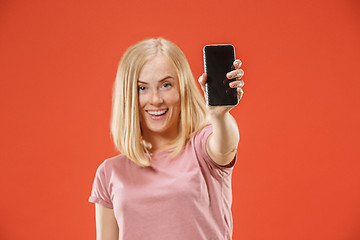 Image showing Portrait of a confident casual girl showing blank screen mobile phone isolated over red background