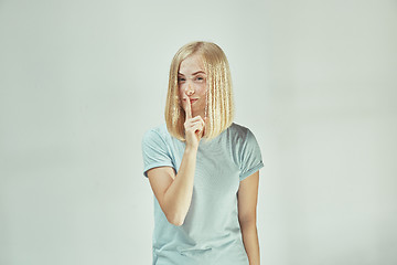 Image showing The young woman whispering a secret behind her hand over gray background