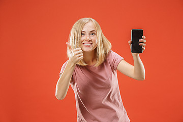 Image showing Portrait of a confident casual girl showing blank screen mobile phone isolated over red background