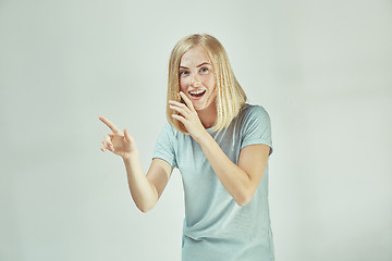 Image showing The young woman whispering a secret behind her hand over gray background