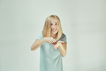 Image showing Beautiful female half-length portrait isolated on gray studio backgroud. The young emotional surprised woman