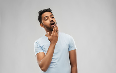 Image showing tired indian man yawning over grey background