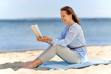 Image showing happy smiling woman reading book on summer beach