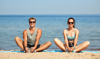 Image showing smiling couple stretching legs on beach