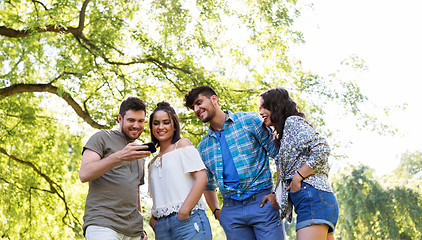 Image showing smiling friends with smartphone in summer park