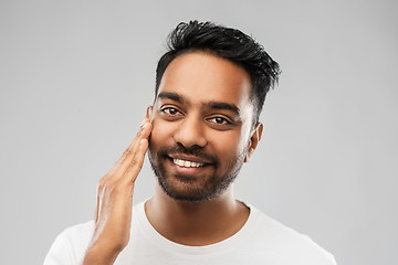 Image showing smiling indian man touching his face