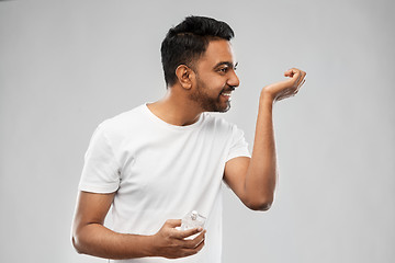 Image showing happy indian man with perfume over gray background