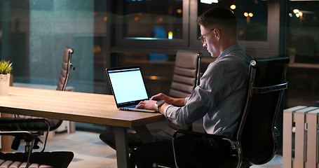 Image showing man working on laptop in dark office