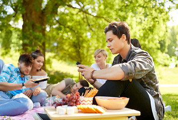 Image showing man using smartphone at picnic with friends