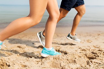 Image showing legs of sportsmen in sneakers running along beach