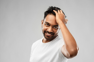 Image showing indian man touching his hair over gray background