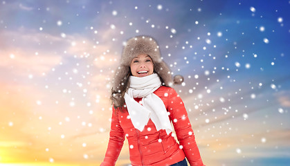 Image showing happy woman in winter fur hat over sky and snow