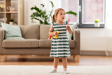 Image showing little girl blowing soap bubbles at home