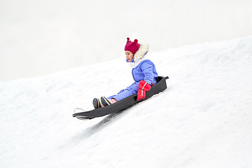 Image showing happy little girl sliding down on sled in winter