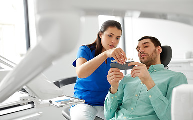 Image showing dentist choosing tooth color for patient at clinic